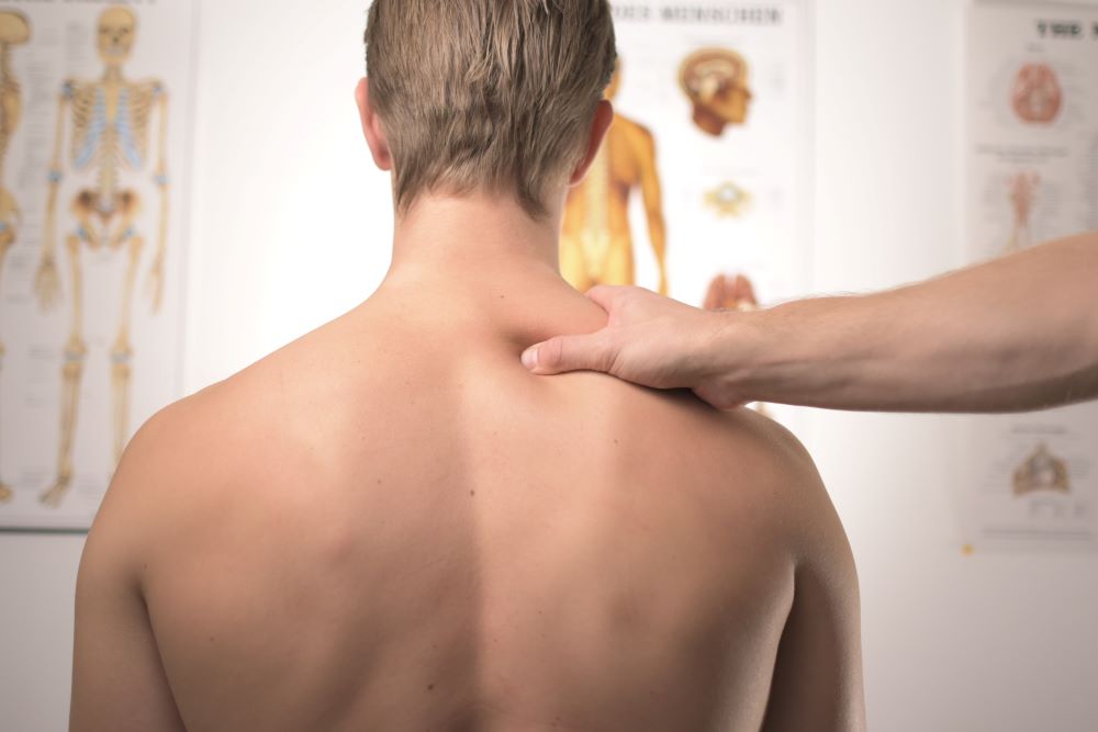 A doctor holds the shoulder of a male patient to test his body's response.